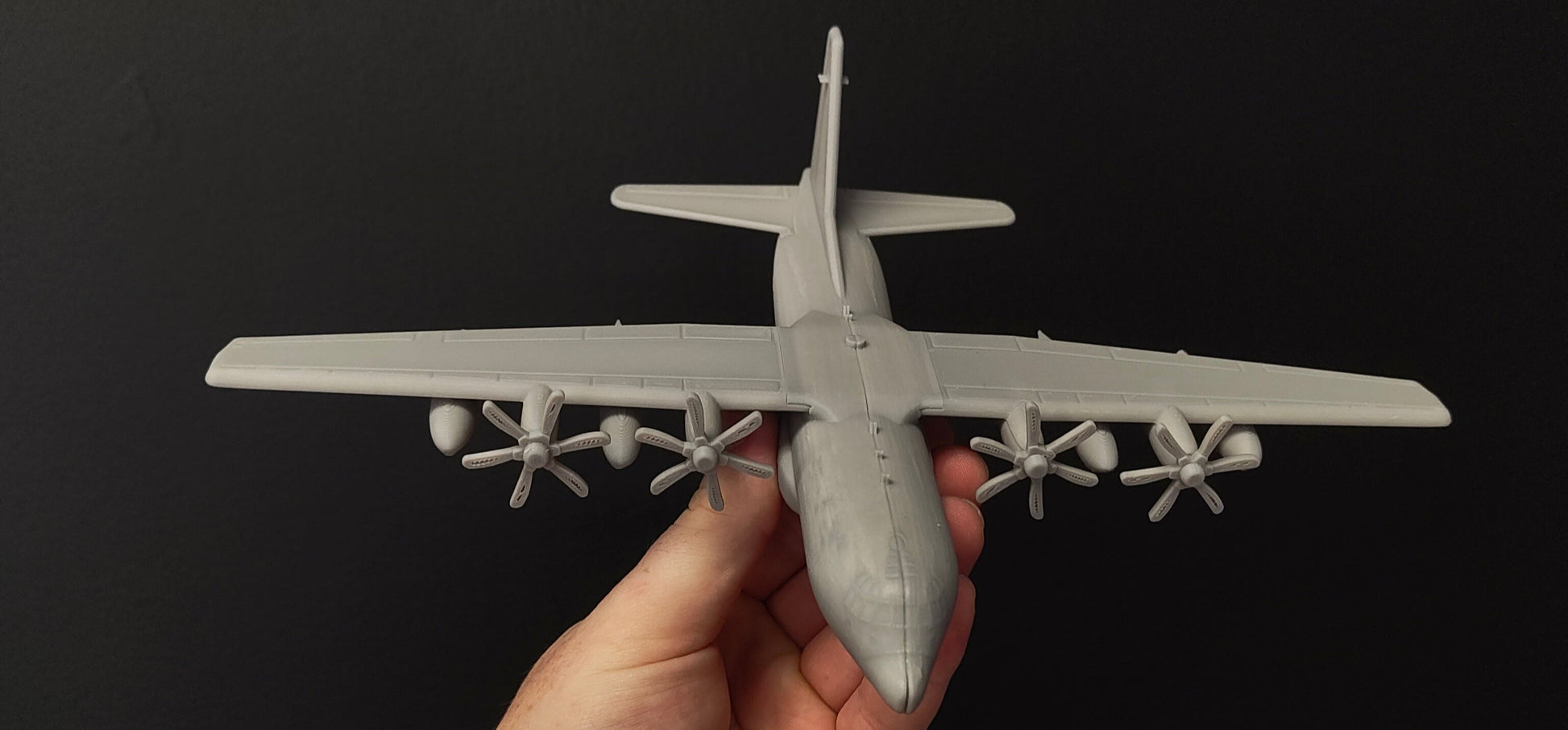Hand holding a model airplane against a black background